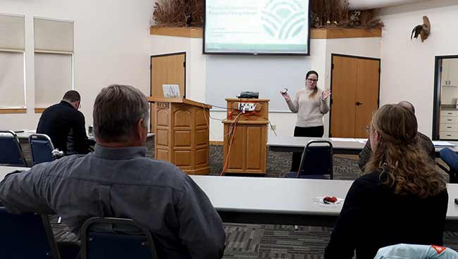 Dr. Molly Gonzales in front of a projection screen speaking to participants.