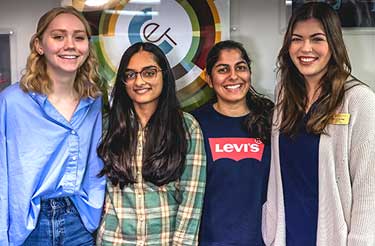 4 student workers pose with smiles in front of the CET logo