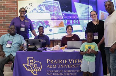 A group of facilitators and participants gathered at a sign-in table for the workshop. The sign reads Prairie View A&M University.