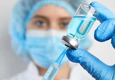 female medical professional loading a syringe from a glass vial